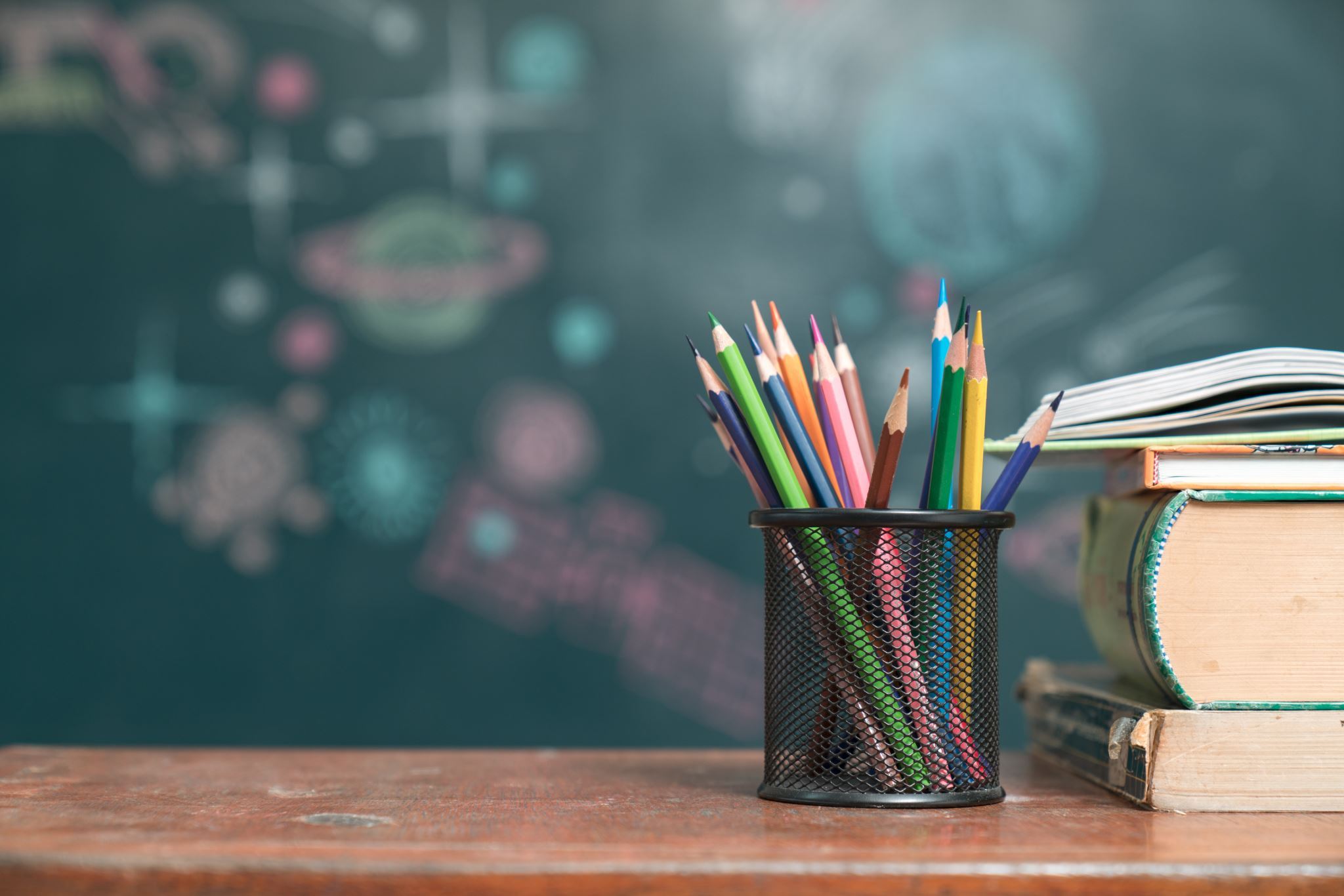 School-desk-with-books-and-pencils-with-chalkboard-in-background